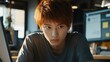 © Darya - 午後のオフィスで、若い男性が真剣な表情でコンピュータの画面を見つめている。