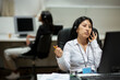 © Jimena Roquero/Stocksy - Woman with headset in office in front of computer looking bored
