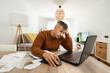 © Alvaro Lavin/Stocksy - Frustrated man doing accounting work holding his head