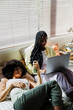 © BONNINSTUDIO/Stocksy - Two women relaxing on bed using laptop and smartphone