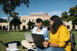 © Pedro Merino/Stocksy - University Students sitting on the grass using laptop