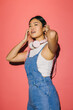 © VICTOR TORRES/Stocksy - Asian woman wearing headphones on pink background looking up joyfully