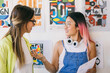 © VICTOR TORRES/Stocksy - Two creative women discussing designs in a colorful modern art studio.