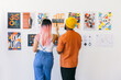 © VICTOR TORRES/Stocksy - Man and woman analyzing creative posters on a white wall