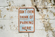 © ALAN SHAPIRO/Stocksy - 'Don't even think of parking here' sign on old cinderblock wall