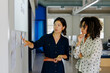 © BONNINSTUDIO/Stocksy - Two businesswomen discussing work strategy in modern office