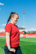 © Jovana Milanko/Stocksy - Happy Female Football Player Smiling on Open-Air Stadium Pitch