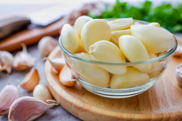 Peeled garlic in a clear bowl and garlic background, close up	