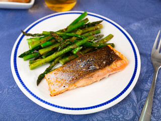 Wall Mural - Tasty grilled salmon steak with asparagus garnish served on white plate