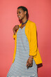 © VICTOR TORRES/Stocksy - Confident woman in yellow blazer and striped dress against pink