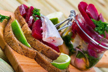 Wall Mural - Blue whiting of home salt pickling in marinade of lime juice and olive oil with beets and greens served on rye bread