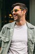 © VICTOR TORRES/Stocksy - Man laughing wearing yellow sunglasses and casual outfit outdoors