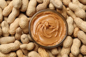 Poster - Tasty peanut butter in bowl among groundnuts, flat lay