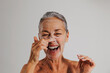 © BONNINSTUDIO/Stocksy - Woman applying moisturizer and smiling