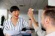 © Jovo Jovanovic/Stocksy - Cheerful colleagues giving high-five in office