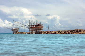 Fototapete - The outer harbour breakwater and a fishing huts (Italian : trabucco). The trabucco is an old fishing machine typical of the Adriatic coast.