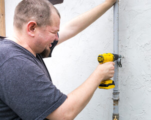 Wall Mural - A man is using a drill to fix a pipe