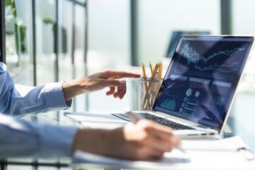 hands of young businesswoman typing computer laptop with graph chart for work.