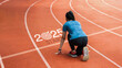 © Dee karen - New year 2025 concept, beginning of success. Text 2025 written on asphalt road and male runner preparing for the new year. Concept of challenge or career path and change.