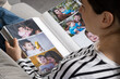 © Zarina Lukash - Woman looking at family photo album about her family.
