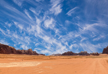 Wadi Rum Desert also known as The Valley of the Moon (against the sky with clouds)-- is a valley cut into the sandstone and granite rock in southern Jordan 60 km to the east of Aqaba