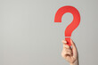 © ALL YOU NEED studio - hand holding up a big red question mark made of paper isolated on clean smooth solid background