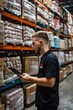 © Fotograf - A person inspecting a tablet in a storage facility or industrial setting