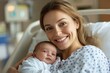 © At My Hat - A woman is holding a baby in a hospital bed. She is smiling and looking at the camera