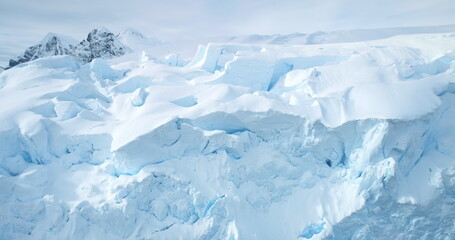 Wall Mural - Massive blue ice wall glacier in Antarctica. Aerial close up fly over snow covered large iceberg surface, bright sunlight. Arctic frozen nature mountain beauty. Winter background. Discover South Pole