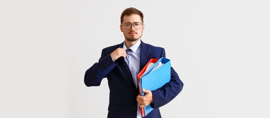 Canvas Print - Young businessman holding folders on light background