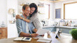 © peopleimages.com - Happy, couple and hug with documents at house for financial planning, bank balance or debt payment. Man, woman or paperwork for budget savings, property insurance and credit score of loan application