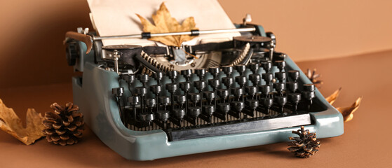 Wall Mural - Vintage typewriter, pine cones and autumn leaves on brown background