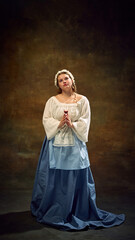 Cubby woman in traditional dress stands gracefully, holding glass of wine, her expression serene against vintage background. Concept of bar, pub, Bavarian style, Oktoberfest. Comparisons of eras.