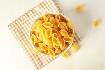 Wall Mural - Bowl with raw conchiglie pasta on light background