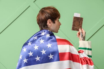 Canvas Print - Handsome young man with USA flag and passport on green background, back view. Immigration concept