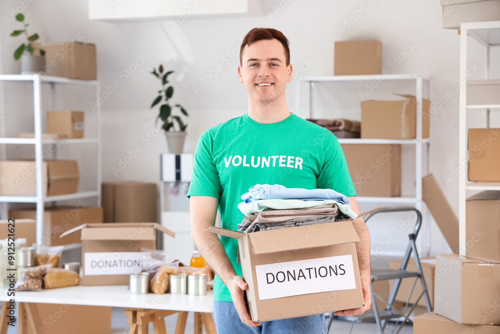 Male volunteer holding donation box with clothes in center