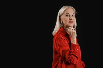 Poster - Fashionable mature woman in beautiful earrings and rings on black background