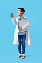 Wall Mural - Cute little boy with clipboard and chemical volcano on blue background