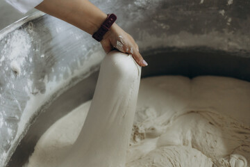 A woman kneads dough at a bread factory