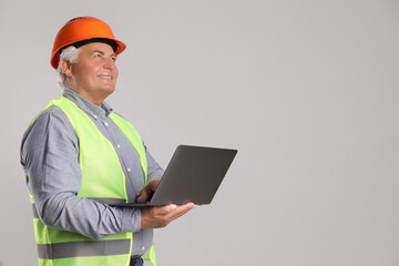 Wall Mural - Engineer in hard hat with laptop on grey background, space for text