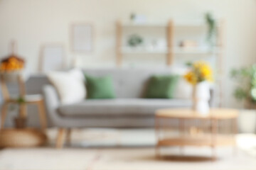 Wall Mural - Cozy sofa and vase with wild flowers on coffee table in interior of living room. Blurred view