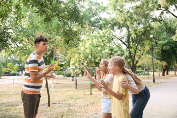 Sticker - Happy family with cute children blowing soap bubbles in park