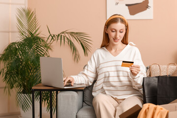 Poster - Young woman with laptop and credit card shopping online on sofa at home