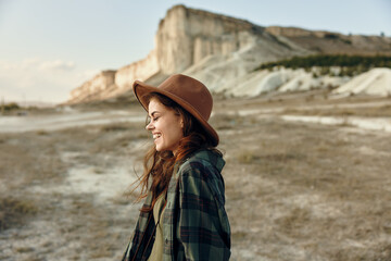 Wall Mural - Outdoor adventure woman in plaid shirt and hat standing in front of majestic mountain range