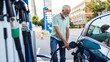 © Jelena Stanojkovic - Cheerful mature businessman filling up car tank with fuel at gas station. Happy mid adult man refueling his car the gas station.