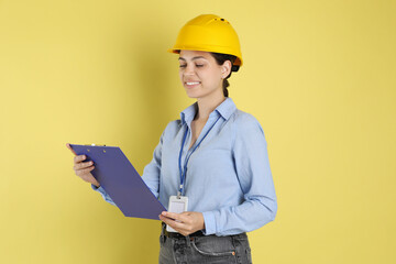 Wall Mural - Engineer in hard hat with clipboard on yellow background