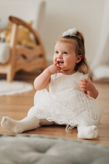 Wall Mural - Cute adorable baby girl in white dress indoors closeup portrait Happy childhood funny kid