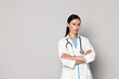 © New Africa - Beautiful nurse with crossed arms on grey background. Space for text