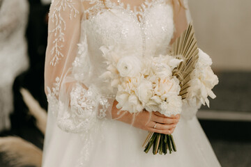 A stunning image of the bride in an elegant dress, holding a charming and delicate bouquet. The photograph captures the beauty and grace of the bride.