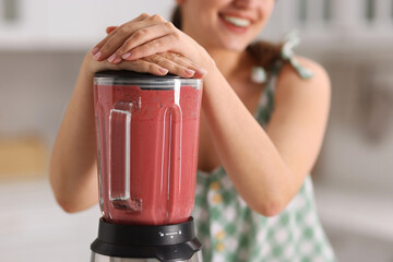 Canvas Print - Woman making delicious smoothie with blender in kitchen, closeup